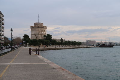 View of buildings by sea against cloudy sky