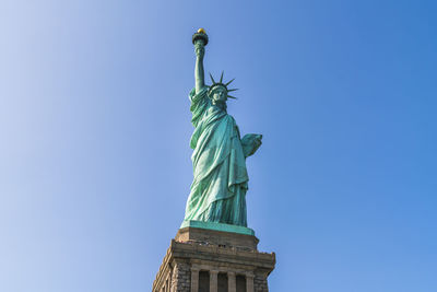 Low angle view of statue of liberty against blue sky