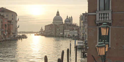 Canal amidst buildings against sky at sunset