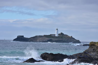 Lighthouse by sea against sky