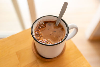 Close up of hot cocoa in white cup in warm morning.