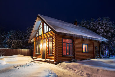 Rustic log house, snow-covered pine trees, snowdrifts, fabulous winter night. new year, christmas.