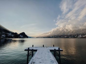 Pier over lake against sky during sunset