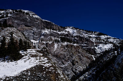 Low angle view of snowcapped mountain against blue sky