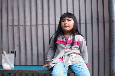 Portrait of a girl standing against wall