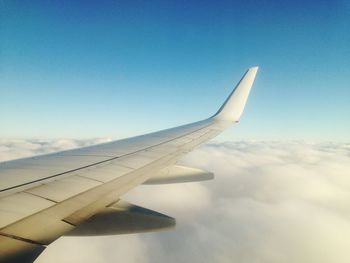 Cropped image of airplane flying over clouds