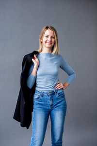 Portrait of smiling young woman standing against wall