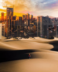 People on street amidst buildings against sky during sunset