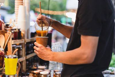 Man barista making healthy latte with turmeric drink at counter bar cafe outdoor.