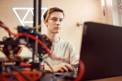 Young man working at laptop. 3d printing concept