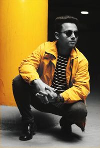 Young man looking away while sitting on wall