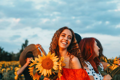 Portrait of a smiling young woman against cloudy sky