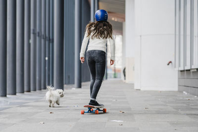 Full length of woman skateboarding on walkway