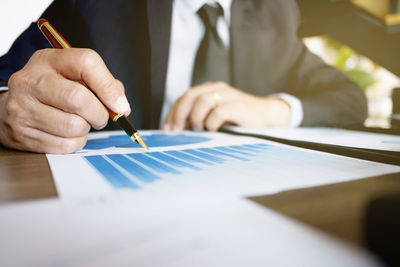 Midsection of man holding umbrella on table