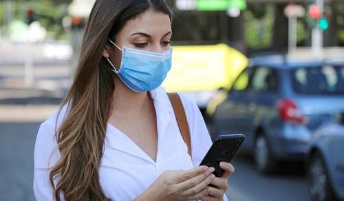 Young woman wearing face mask while using mobile phone