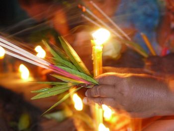 Close-up of hand holding lit candles