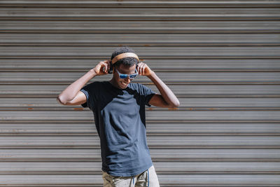 Portrait of man wearing sunglasses standing against wall