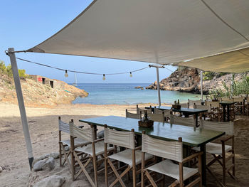 Chairs and table on beach against sky