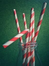 Close-up of red and white striped straws in glass bottle