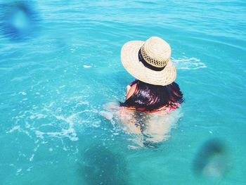 Rear view of woman swimming in turquoise sea