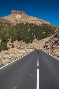 Road leading towards mountain against sky