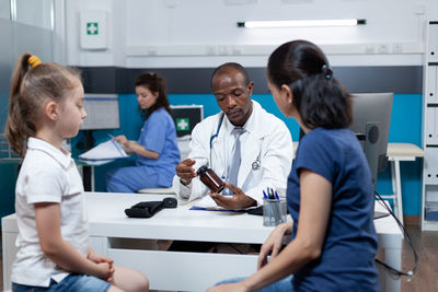 Doctor prescribing medicine to patient and mother at clinic