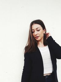 Beautiful young woman standing against white background