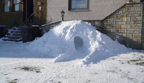 Snow covered house on field by building