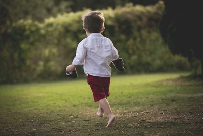 Rear view of boy running on field