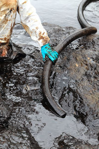 Midsection of male worker holding pipe in mud