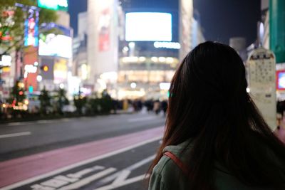 Rear view of woman on street at night