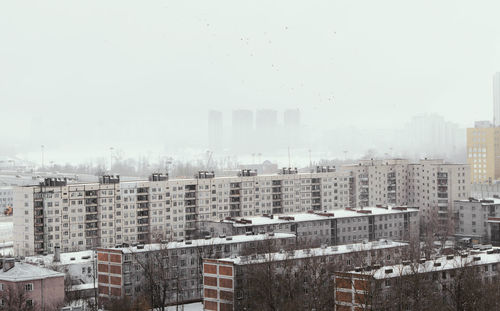 Buildings in city against sky during winter
