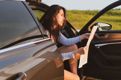 Young woman sitting on car