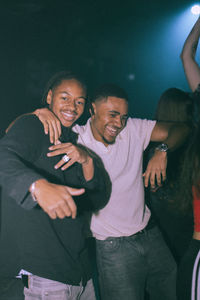 Portrait of cheerful young man dancing with male friend at nightclub