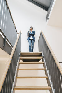 Confident businesswoman with long grey hair standing on top of stairs