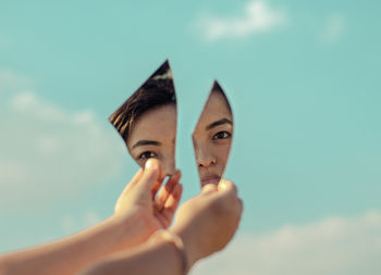 Low angle portrait of woman hand against sky