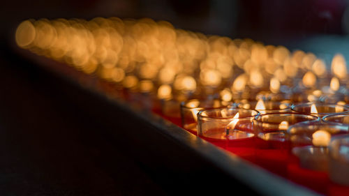 Close-up of lit candles arranged on table
