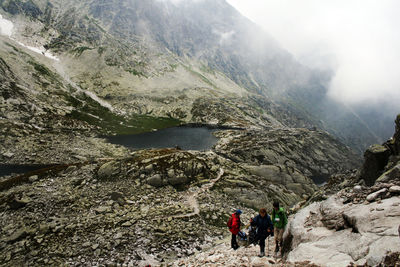 People on mountain by lake against sky