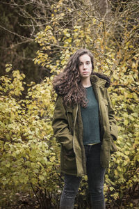 Portrait of young woman standing in autumn leaves