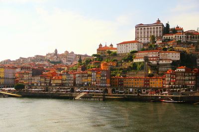 Buildings by river against sky in town