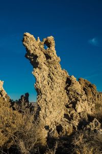 Low angle view of rocks against clear blue sky