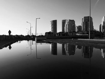Reflection of buildings in city against clear sky