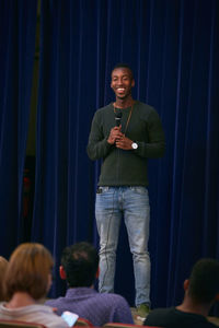 Young man singing into microphone in auditorium