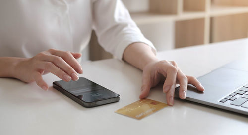 Midsection of woman using smart phone on table