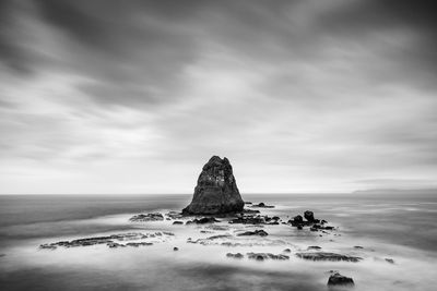 Rock formation on beach against sky