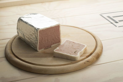 Liver-cheese in aluminium film served on a wooden plate