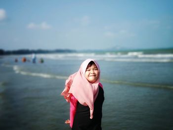 Portrait of smiling young woman standing in sea