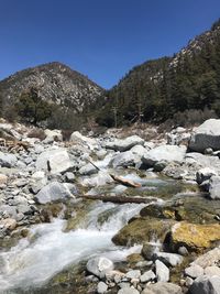 Scenic view of river by mountains against clear sky