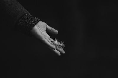 Close-up of hand holding light over black background