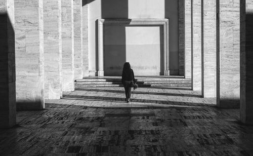 Rear view of woman sitting on staircase against building